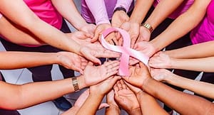 Breast cancer ribbon held by 14 hands in a circle
