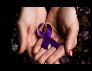 Hands holding a purple domestic violence ribbon