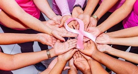 Breast cancer ribbon held by 14 hands in a circle
